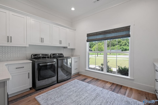 laundry room with washing machine and dryer, hardwood / wood-style floors, and cabinets