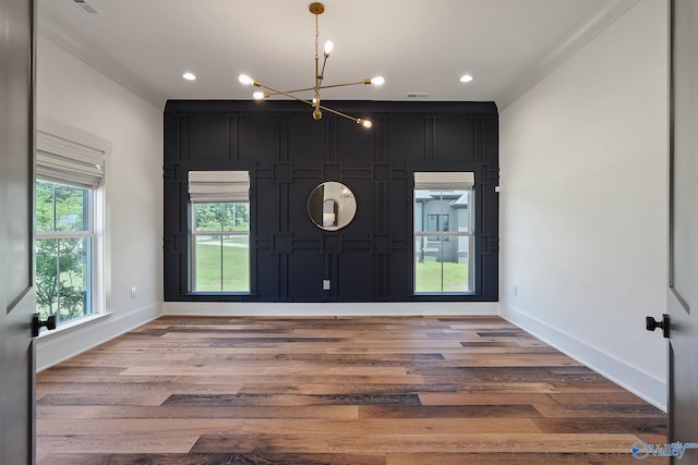 foyer entrance featuring ornamental molding, a notable chandelier, and hardwood / wood-style flooring