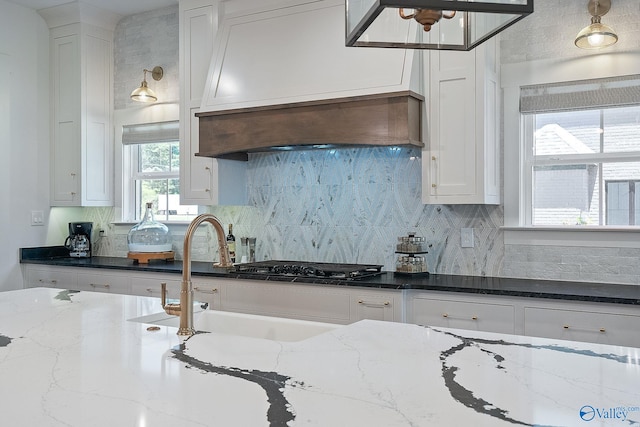 kitchen with dark stone countertops, white cabinets, and backsplash