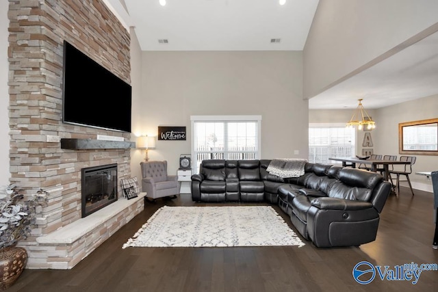 living room with dark hardwood / wood-style flooring, a stone fireplace, and a high ceiling