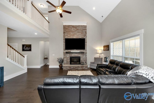 living room featuring dark hardwood / wood-style flooring, a stone fireplace, high vaulted ceiling, and ceiling fan