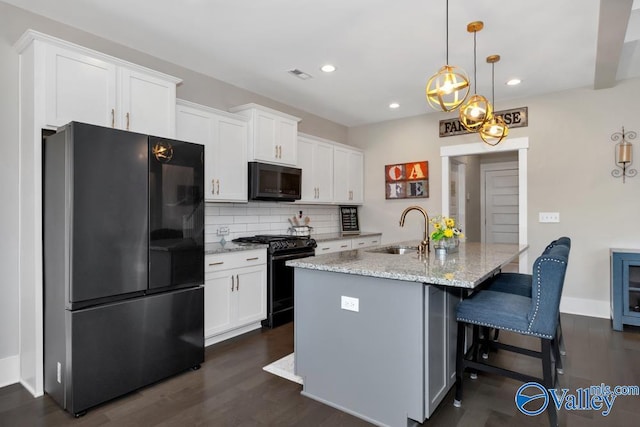 kitchen featuring light stone counters, sink, black appliances, and white cabinets