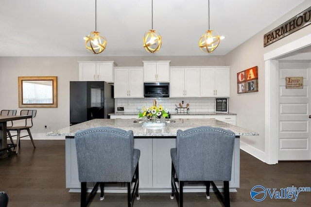 kitchen with pendant lighting, white cabinetry, and black fridge