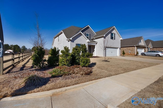 view of front facade featuring a garage, driveway, fence, and a residential view