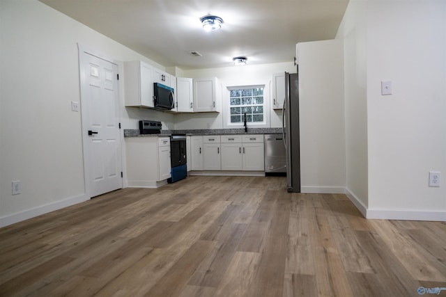 kitchen featuring sink, white cabinets, light stone counters, stainless steel appliances, and light wood-type flooring