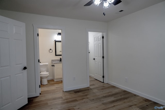 unfurnished bedroom featuring ensuite bath and light hardwood / wood-style flooring