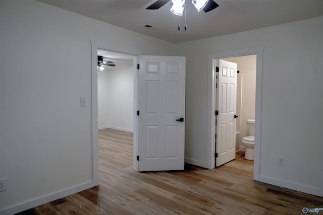unfurnished bedroom featuring ceiling fan, ensuite bath, and light hardwood / wood-style floors