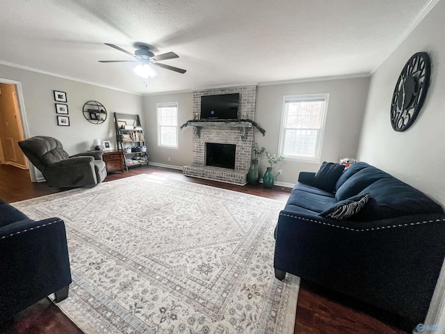 living room with dark hardwood / wood-style floors, a fireplace, ceiling fan, crown molding, and a textured ceiling