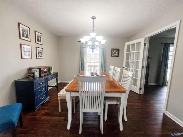 dining space featuring a notable chandelier, dark wood-type flooring, and a textured ceiling