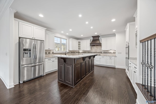 kitchen with premium range hood, appliances with stainless steel finishes, a kitchen island, white cabinetry, and a kitchen breakfast bar