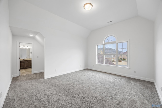 interior space featuring lofted ceiling, carpet floors, sink, and ensuite bath