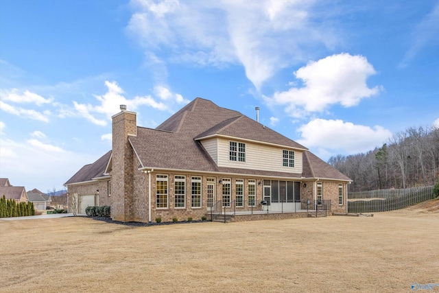 rear view of house with a garage, a sunroom, and a lawn