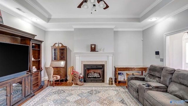 living area with a fireplace, visible vents, wood finished floors, and a tray ceiling