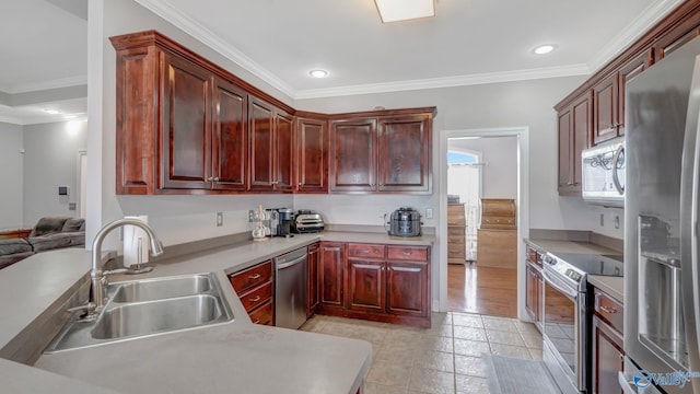 kitchen with reddish brown cabinets, stainless steel appliances, light countertops, ornamental molding, and a sink