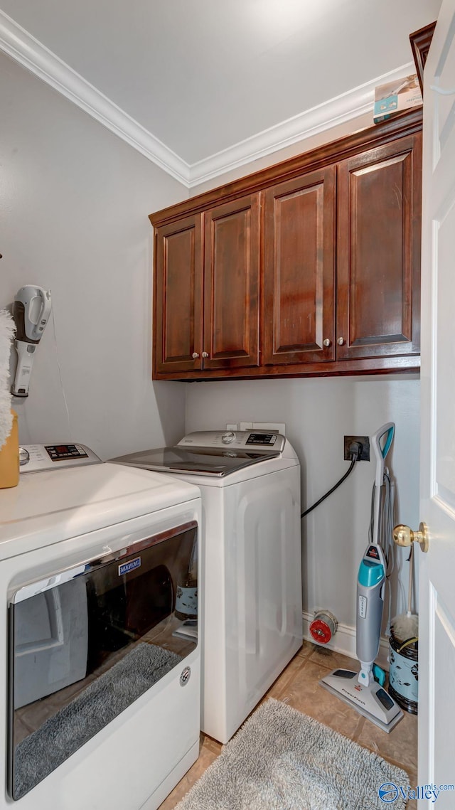 laundry area featuring light tile patterned flooring, cabinet space, crown molding, and washing machine and clothes dryer