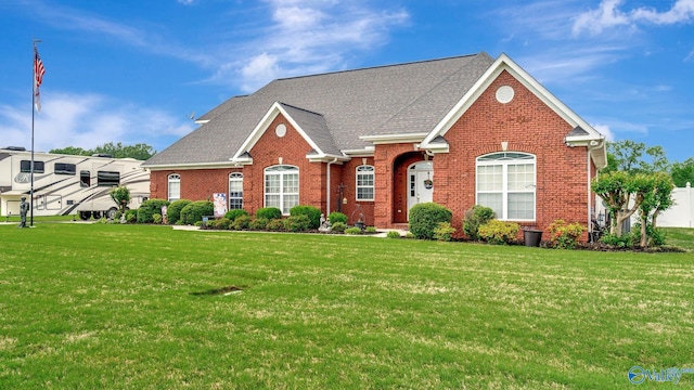 view of front of house featuring a front lawn, roof with shingles, and brick siding