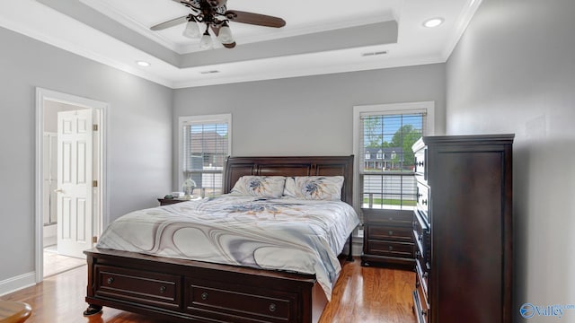 bedroom featuring a raised ceiling, visible vents, and crown molding