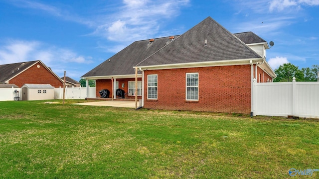 rear view of house with a patio area, a yard, brick siding, and a fenced backyard