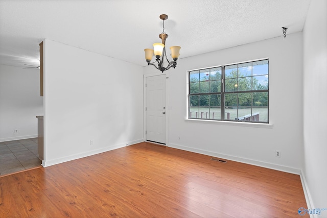 spare room featuring hardwood / wood-style flooring, a notable chandelier, and a textured ceiling