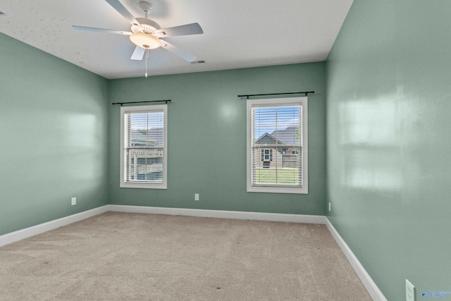 spare room featuring light carpet, a ceiling fan, and baseboards