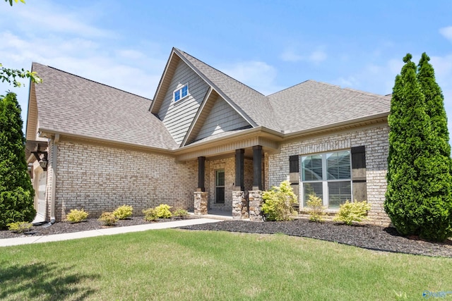 view of front of house featuring brick siding, a front yard, a shingled roof, and a porch