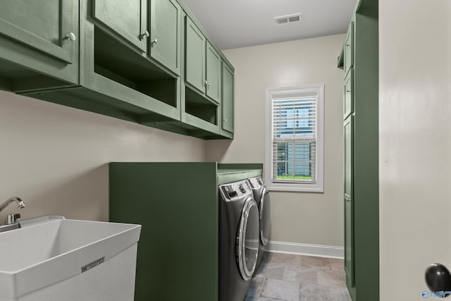 clothes washing area featuring separate washer and dryer, baseboards, and cabinet space