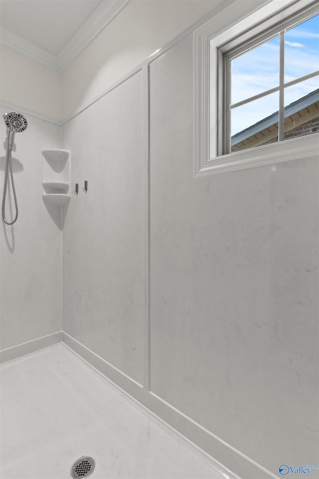 bathroom with ornamental molding and a tile shower