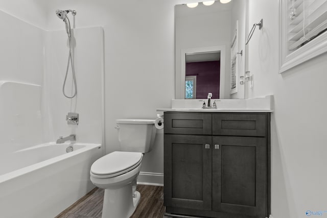 full bath featuring toilet, wood finished floors, baseboards, vanity, and washtub / shower combination