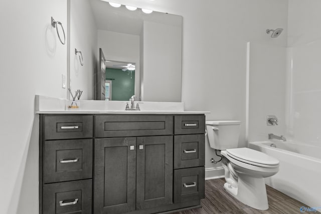 bathroom with baseboards, vanity, wood finished floors, shower / tub combination, and toilet