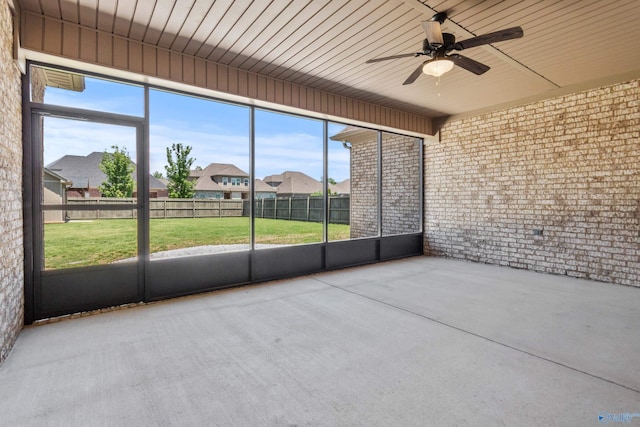 unfurnished sunroom with ceiling fan and a residential view