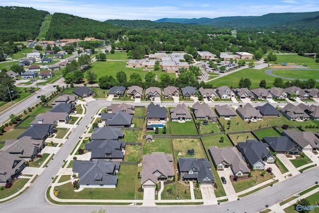 view of property location featuring a mountain backdrop, a forest, and nearby suburban area