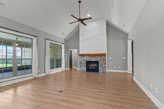 unfurnished living room featuring a ceiling fan, high vaulted ceiling, a fireplace, light wood-style floors, and baseboards