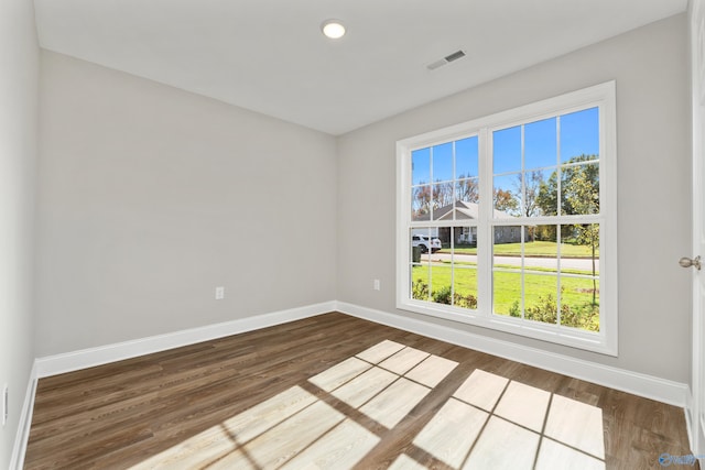 unfurnished room with dark wood-style floors, visible vents, and baseboards