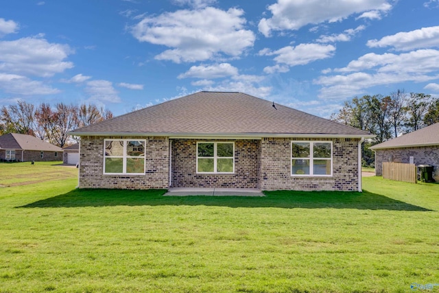 rear view of house with a yard, brick siding, and a patio area