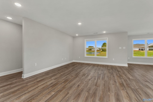 unfurnished living room with plenty of natural light, baseboards, dark wood finished floors, and recessed lighting