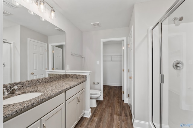 full bath featuring wood finished floors, a walk in closet, visible vents, and a shower stall