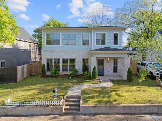 view of front of property featuring brick siding, a front lawn, and fence