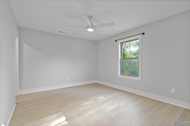 spare room with baseboards, a ceiling fan, visible vents, and light wood-style flooring