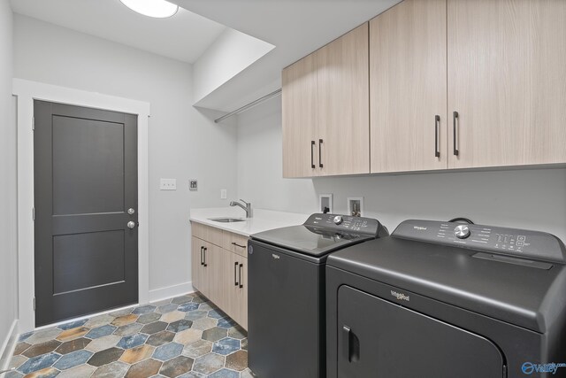 washroom featuring cabinet space, baseboards, separate washer and dryer, and a sink