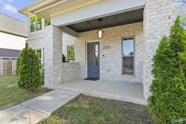 property entrance with fence and brick siding