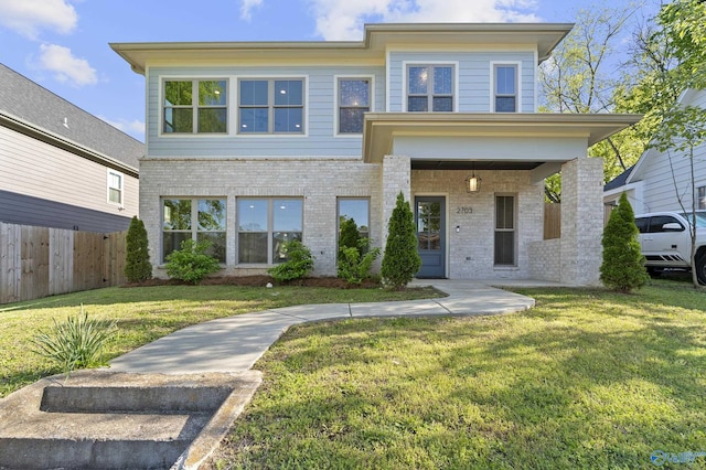view of front of house with brick siding, a front yard, and fence