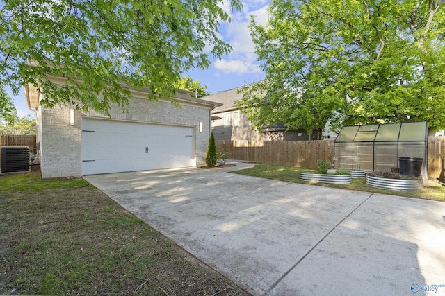 garage with central air condition unit, fence, and concrete driveway