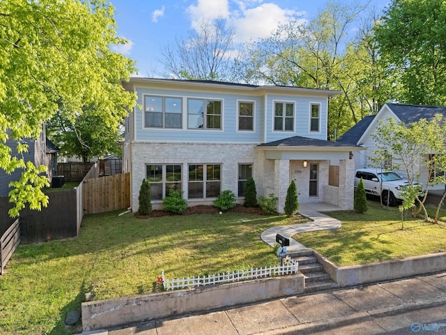 traditional-style house with brick siding, a front yard, and fence