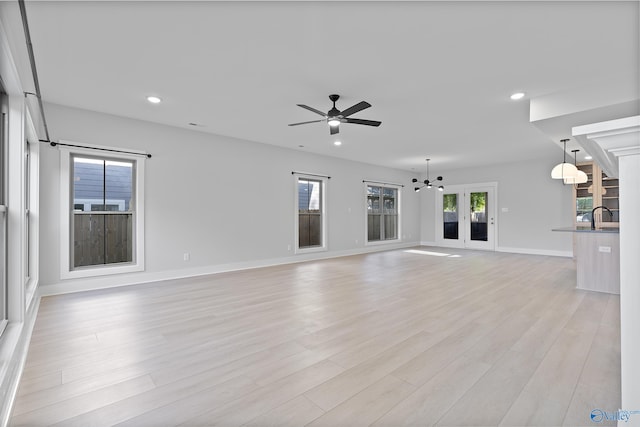 unfurnished living room with recessed lighting, light wood finished floors, ceiling fan, and a sink