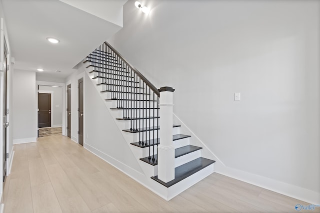 stairway featuring recessed lighting, wood finished floors, and baseboards