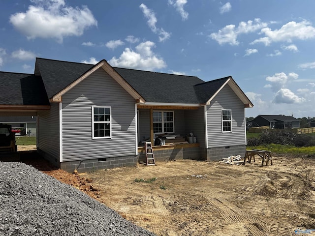 rear view of property featuring a shingled roof, covered porch, and crawl space