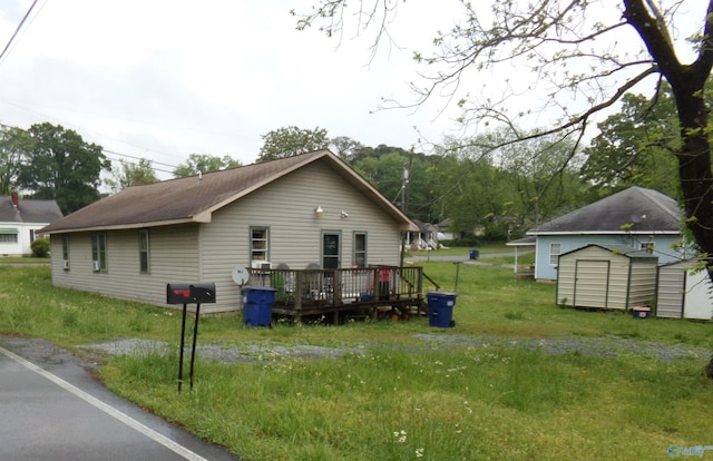 view of property exterior with an outdoor structure, a lawn, a deck, and a storage unit