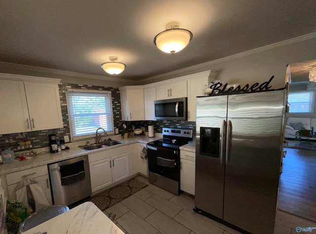 kitchen with white cabinets, tasteful backsplash, sink, crown molding, and stainless steel appliances