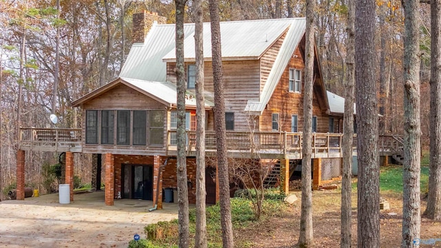 back of house with a sunroom, a deck, and a carport