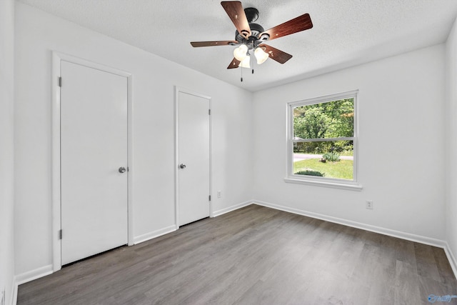 unfurnished bedroom featuring baseboards, a textured ceiling, and wood finished floors